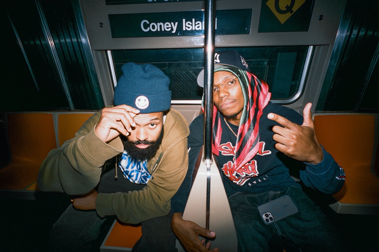 Adé Hakim and another passenger seated together inside a New York subway car.