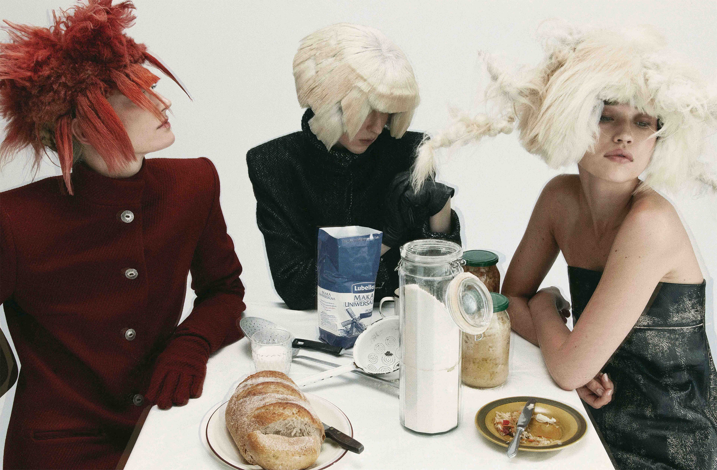 Three models wearing textured headpieces and tailored garments from Barbora Necpalová’s I Season With Ants, seated around a table.