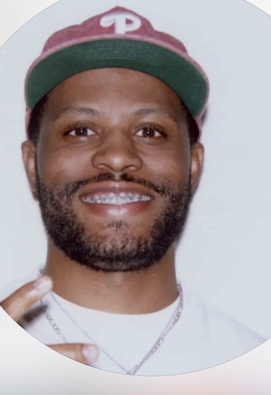 Close-up portrait of Nassir Saleem wearing a burgundy Philadelphia baseball cap