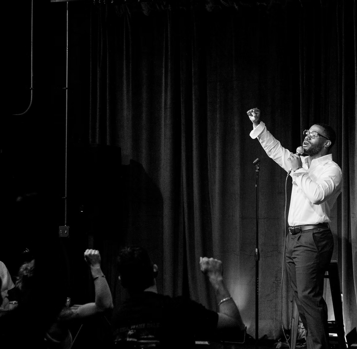 Black-and-white photograph of Nassir Saleem addressing a live audience
